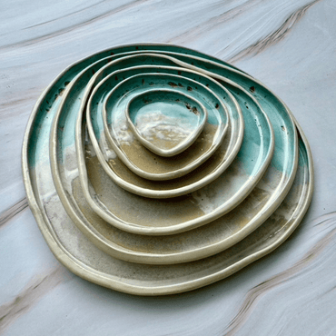 Stack of ceramic plates with green and beige glaze on a marble surface