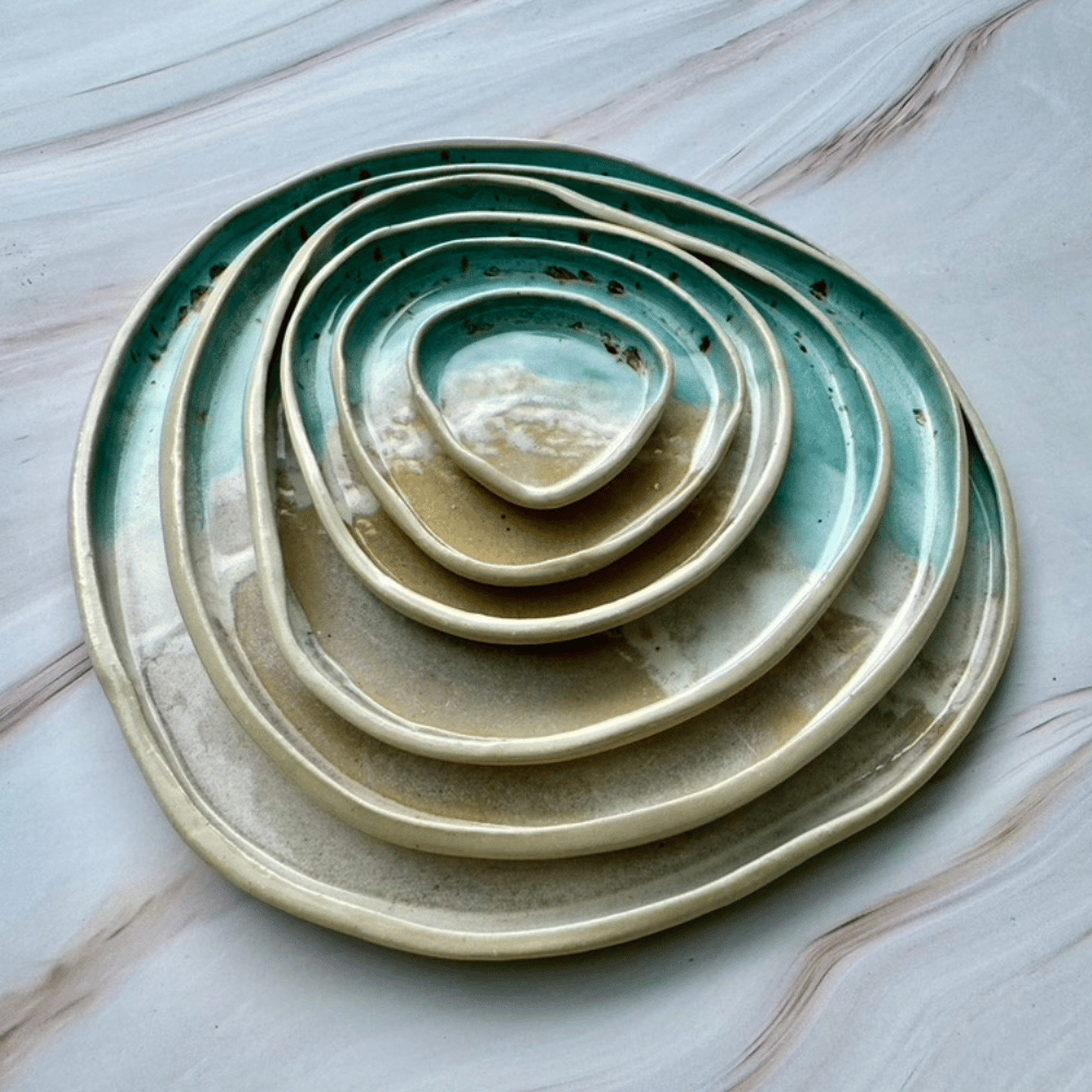 Stack of ceramic plates with green and beige glaze on a marble surface