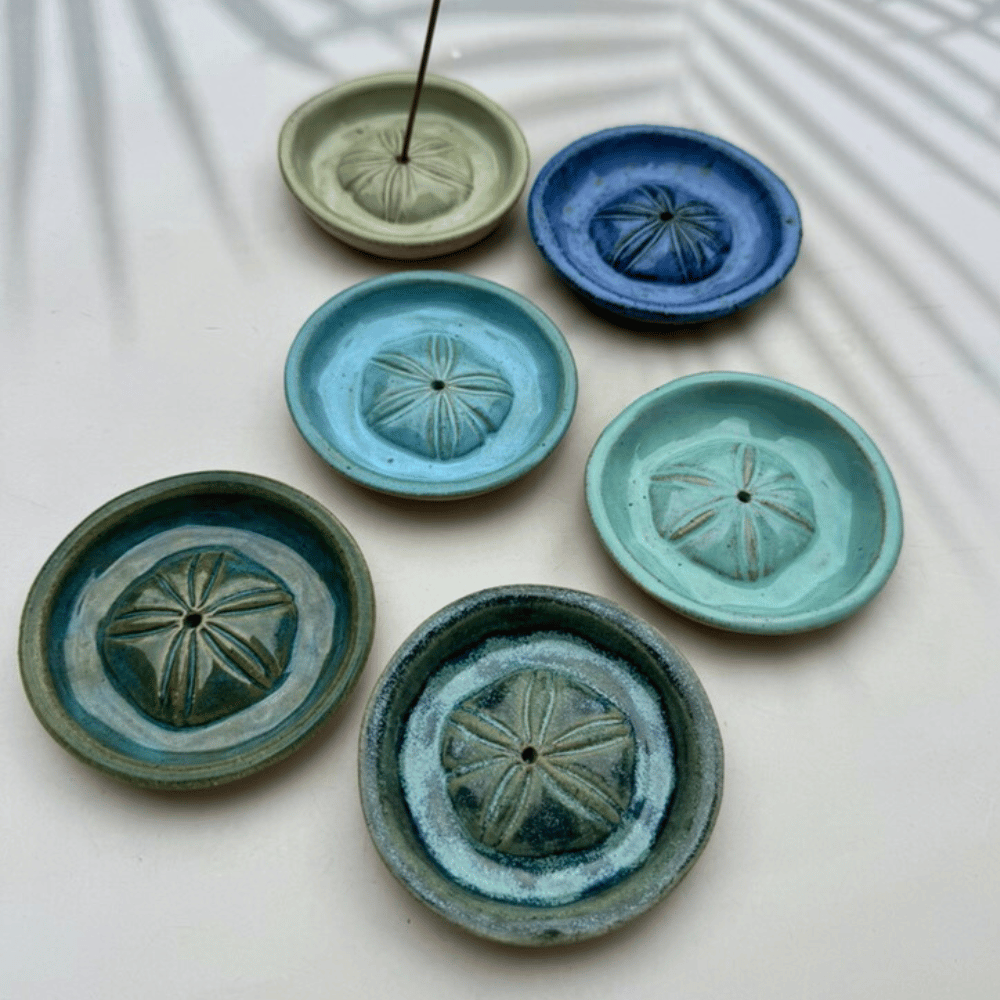 Set of ceramic incense holders in various colors on a light background