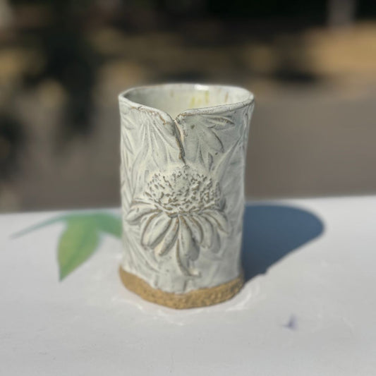 Ceramic vase with coneflower design on a blurred background