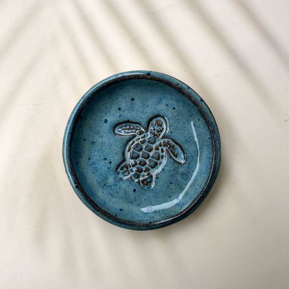 Blue ceramic trinket dish with a turtle design on a beige background
