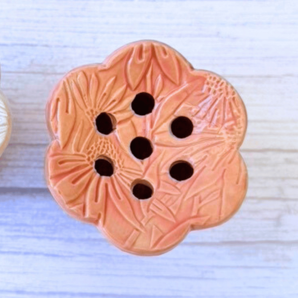 Decorative pink flower frog vase topper with floral pattern on a light blue background