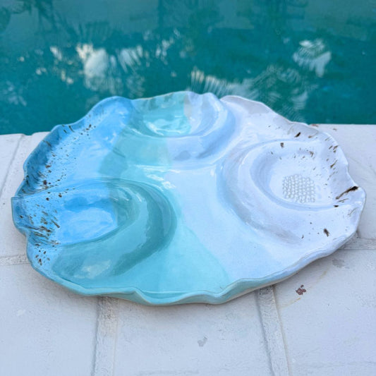 Shell-shaped blue and white dish on a pool ledge