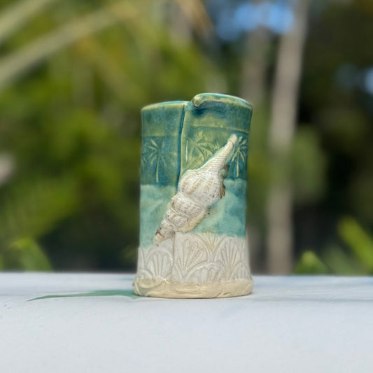 Ceramic vase with shell design on a blurred natural background