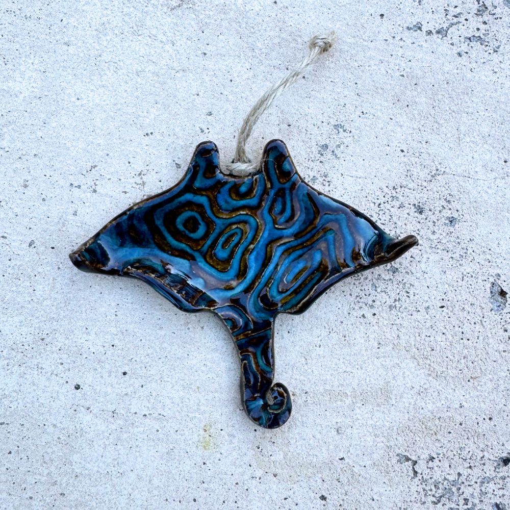 Blue and black ceramic stingray ornament on a textured white surface