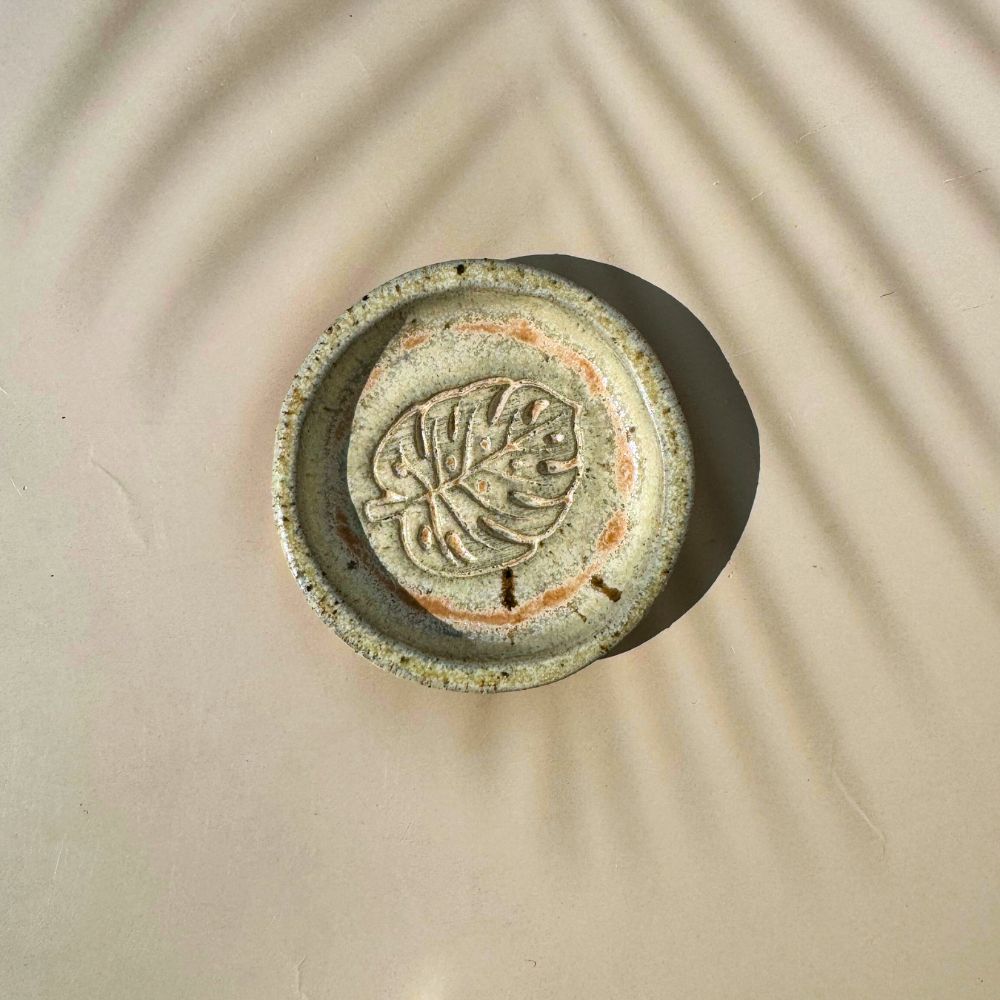 Ceramic ring dish with leaf design on a beige background