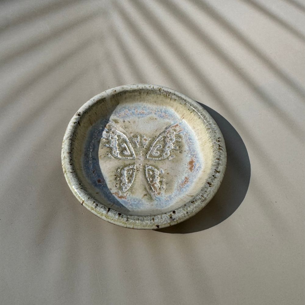 Ceramic ring dish with butterfly design on a textured surface