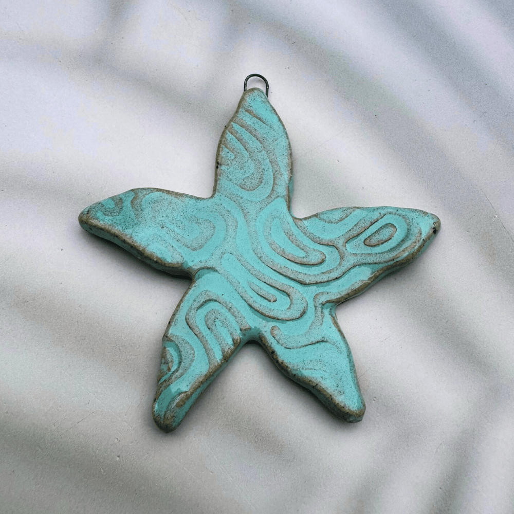 Turquoise ceramic starfish pendant on a light background