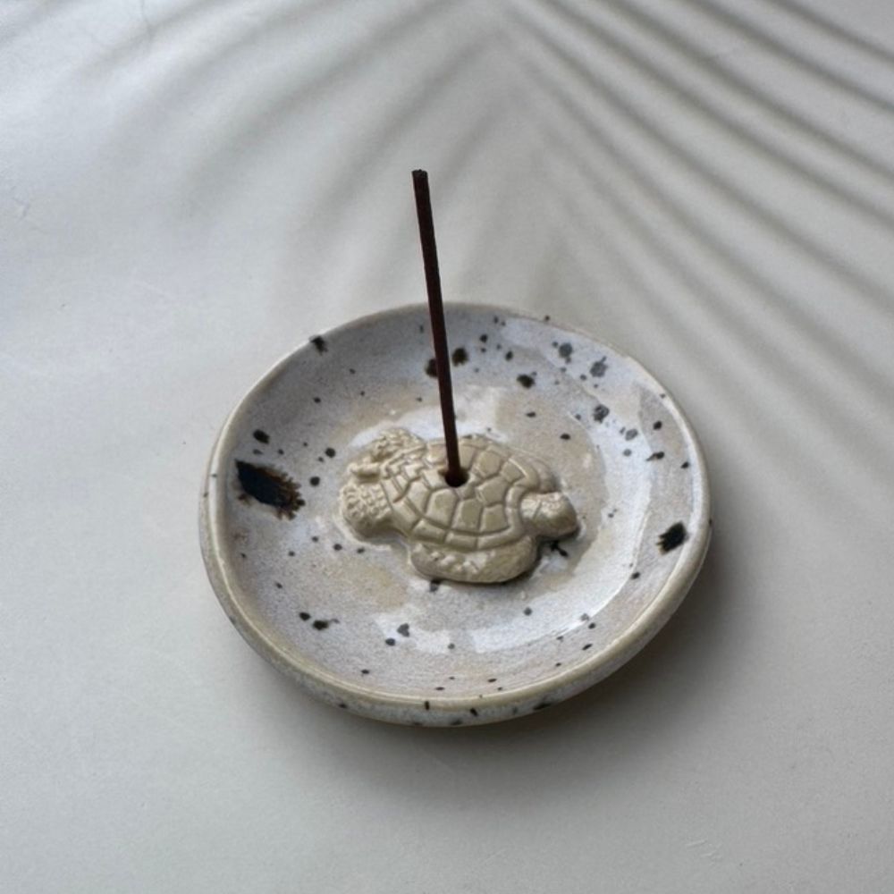 Ceramic incense holder with turtle design on a white surface