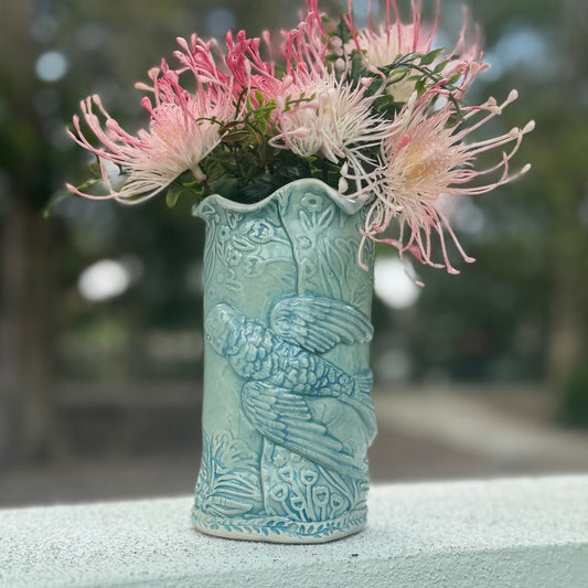 Decorative ceramic vase with bird and floral texture with floral arrangement on a blurred natural background