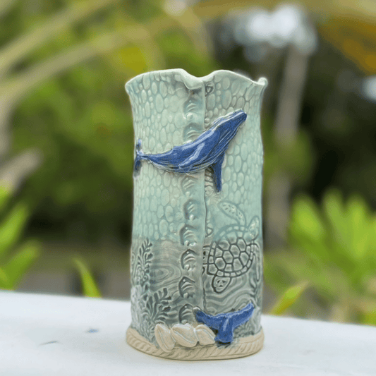 Ceramic vase with whale designs on a blurred natural background