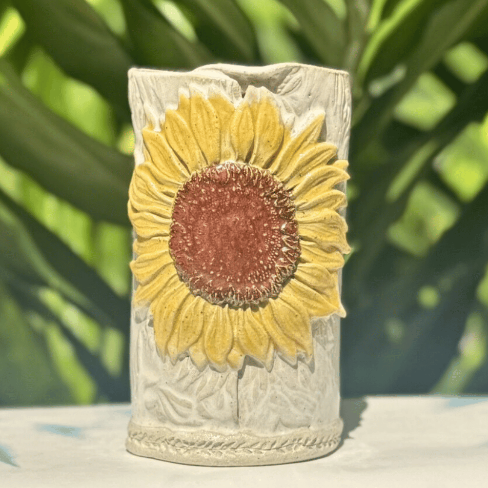 Decorative vase with a sunflower design on a blurred green background