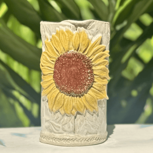 Decorative vase with a sunflower design on a blurred green background
