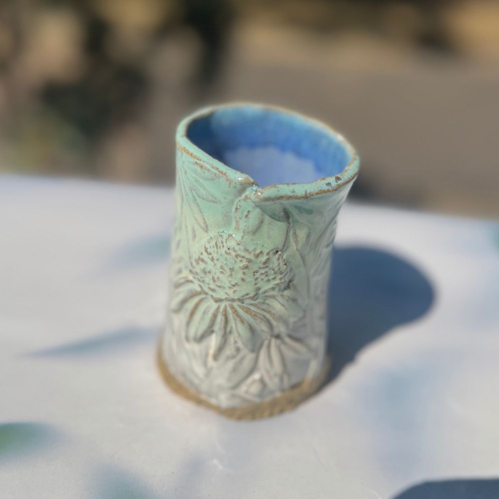 Ceramic vase with floral design on a blurred natural background