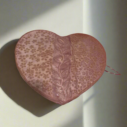 Heart-shaped pink pillow with floral pattern on a beige background