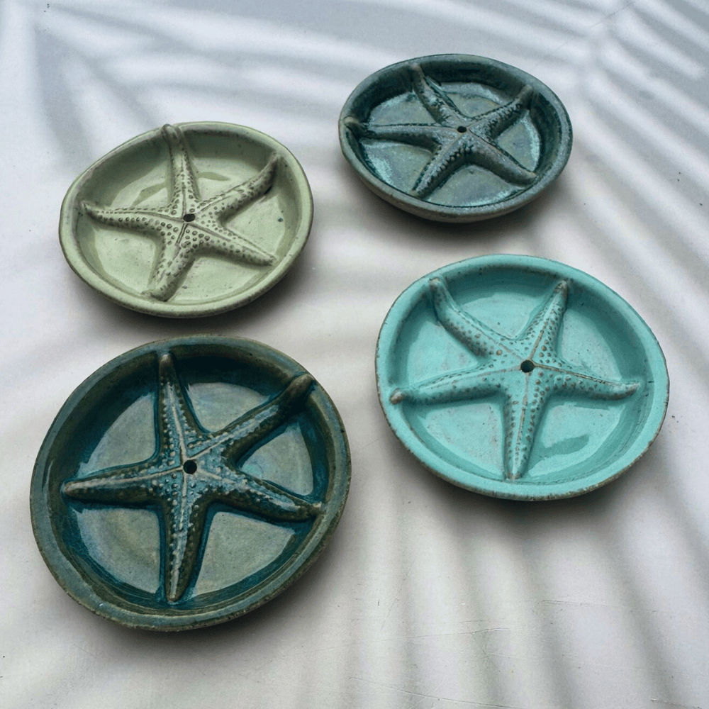 Four ceramic plates with starfish designs on a textured surface