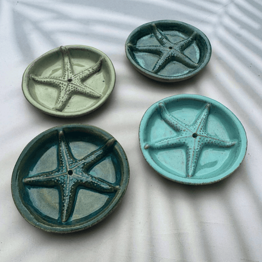 Four ceramic plates with starfish designs on a textured surface