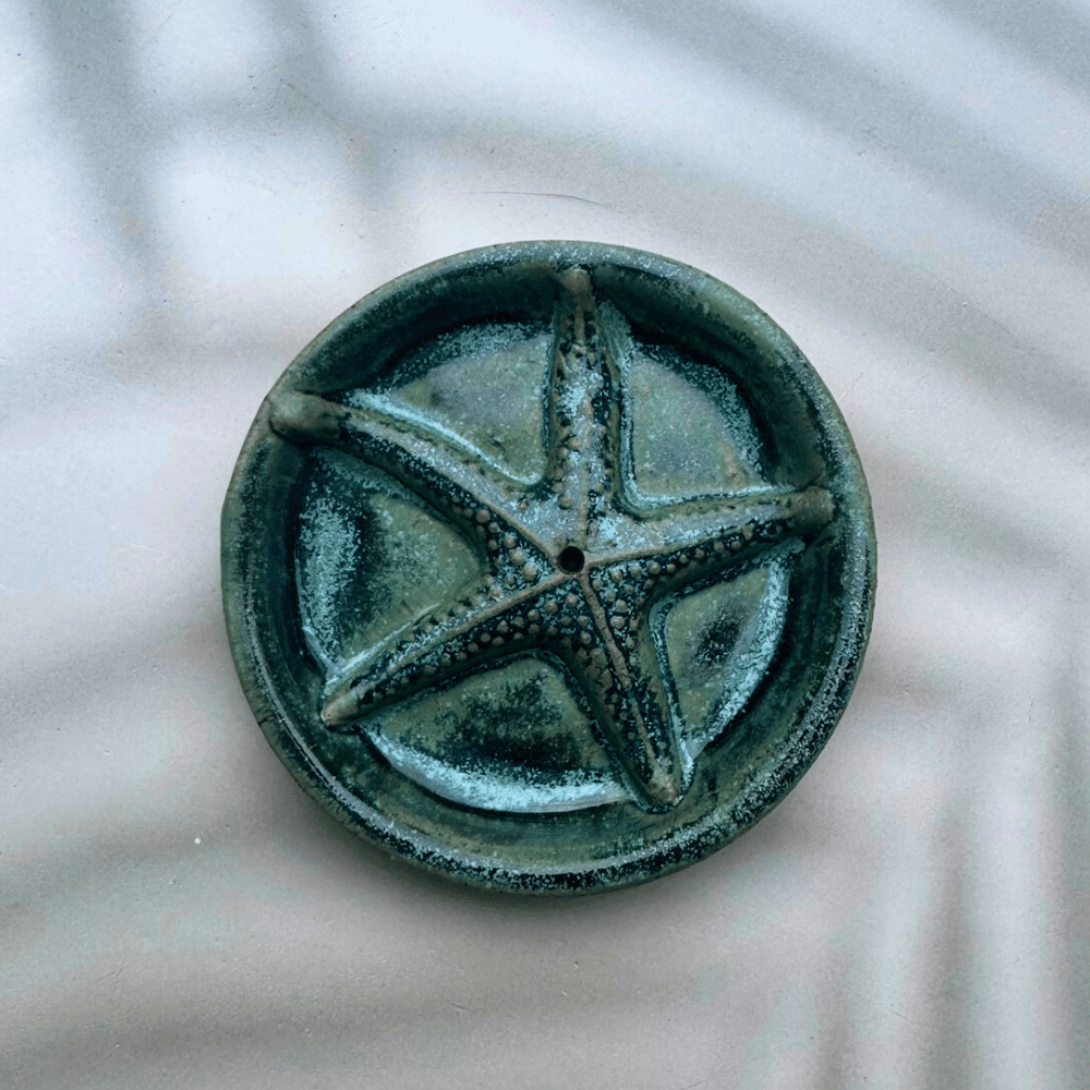 Green ceramic pentacle on a textured white background