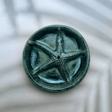 Green ceramic pentacle on a textured white background