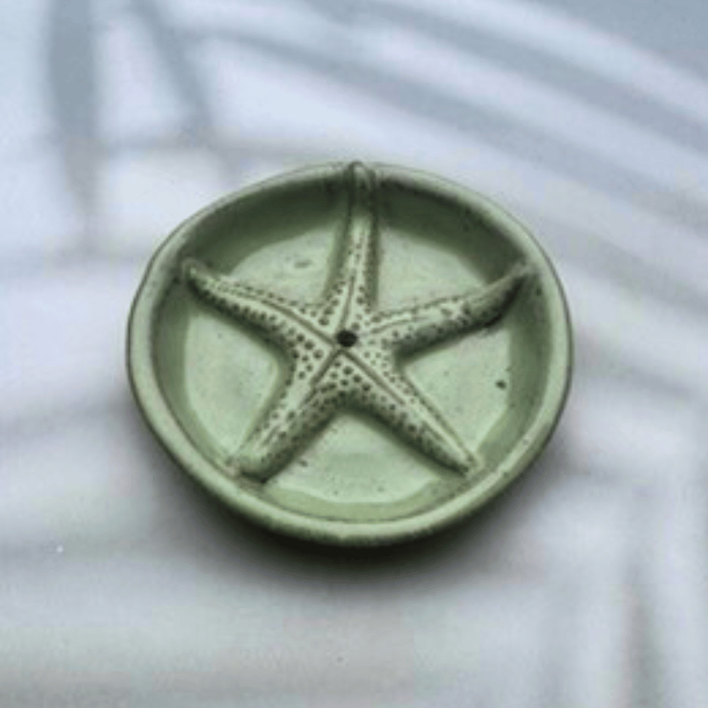 Green ceramic holder with a starfish design on a light background