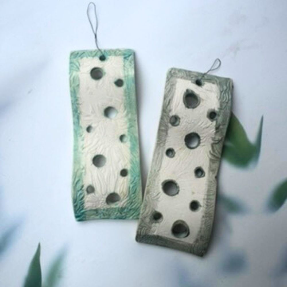 Two rectangular air plant holders with hole patterns on a light background