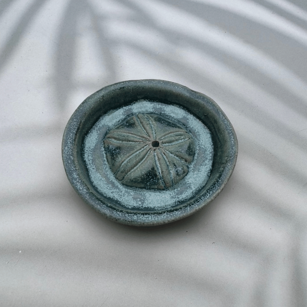 Ceramic incense burner with sand dollar design on a textured surface