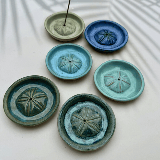 Set of ceramic incense holders in various colors on a light background