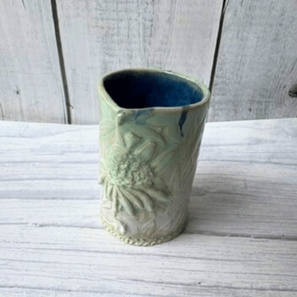 Decorative ceramic bud vase with textured design on a white wooden surface