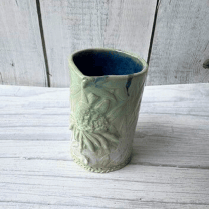 Decorative ceramic bud vase with textured design on a white wooden surface