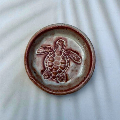 Ceramic dish with a turtle design on a textured white background