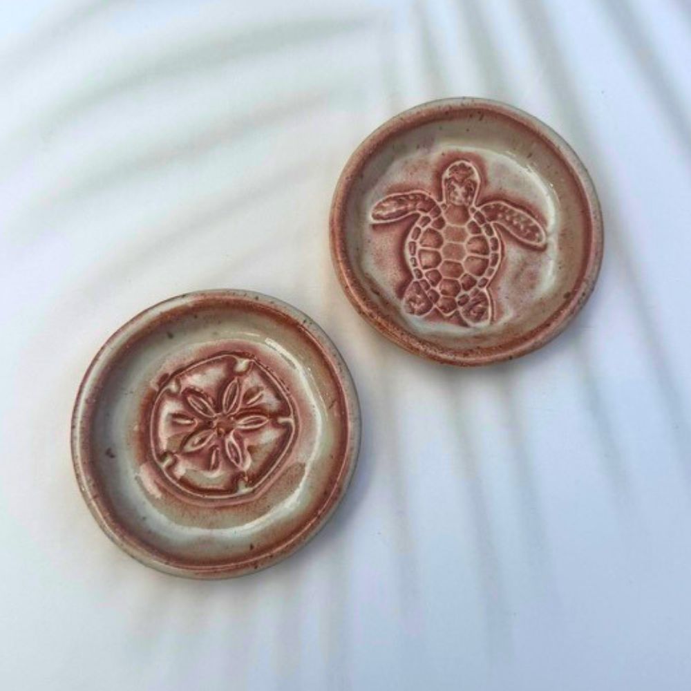 Two ceramic plates with embossed designs on a white background