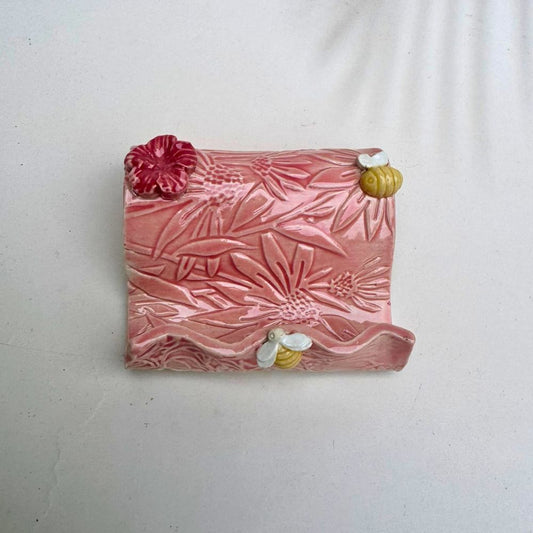 Pink textured business card holder  with floral designs on a white background