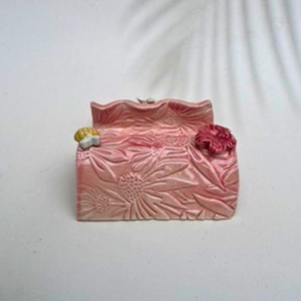 Pink textured business card holder  with floral designs on a white background