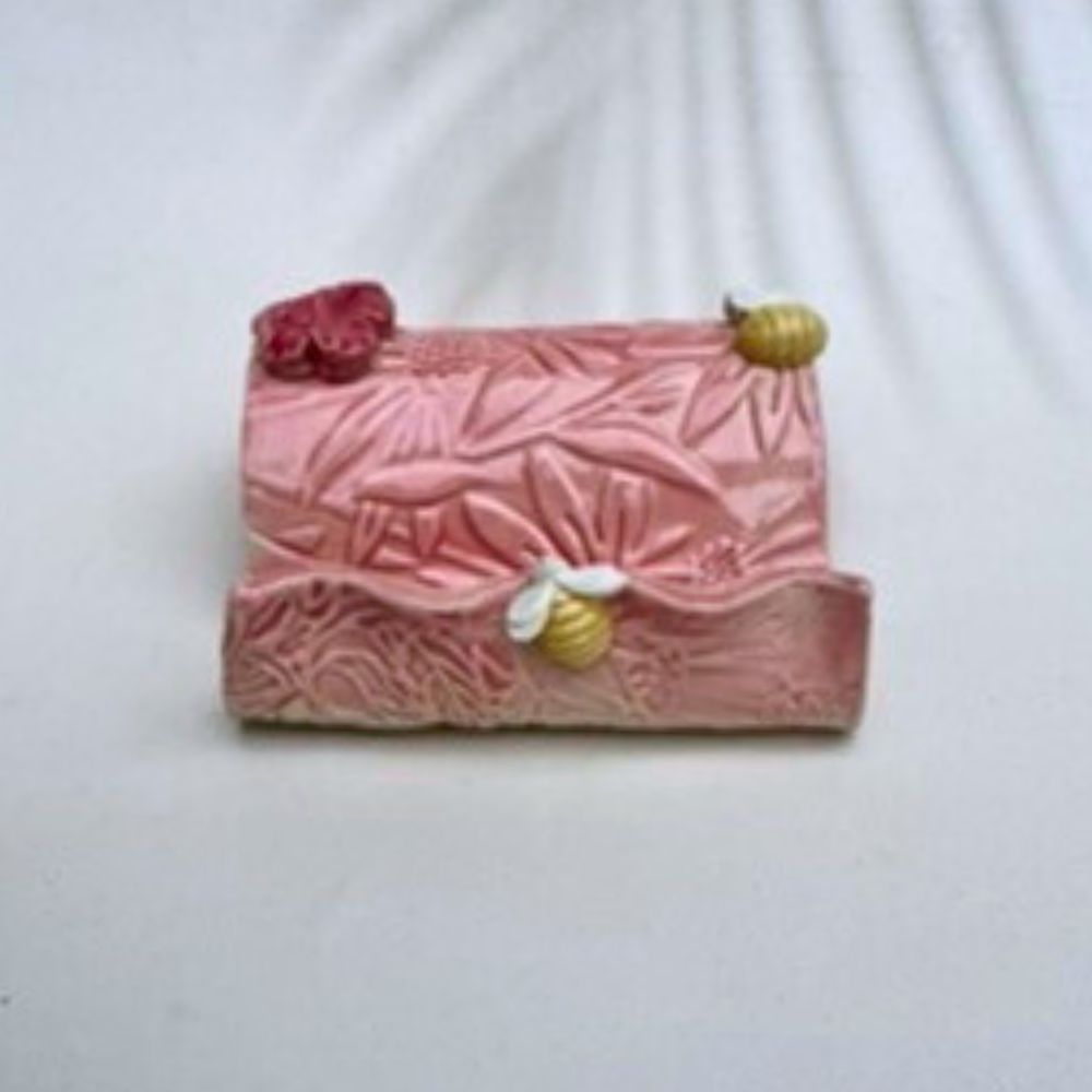 Pink textured business card holder  with floral designs on a white background