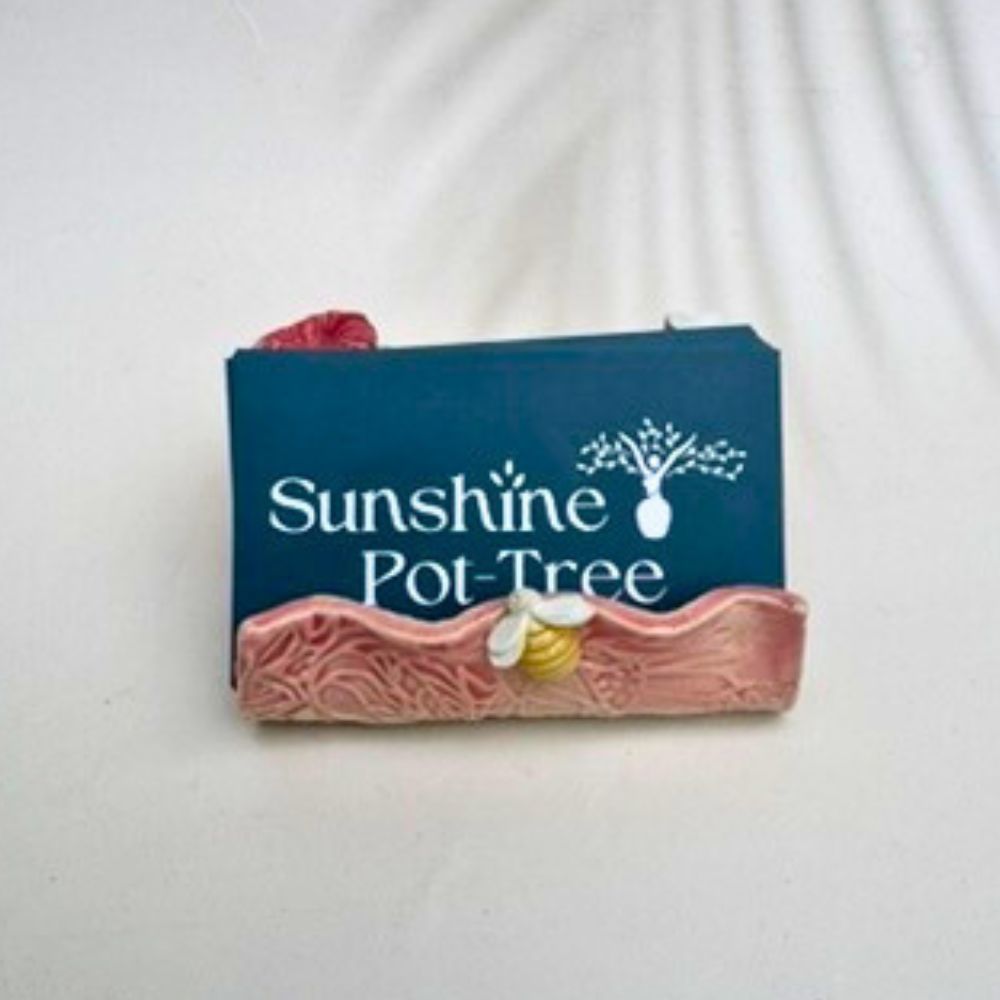 Pink textured business card holder  with floral designs on a white background