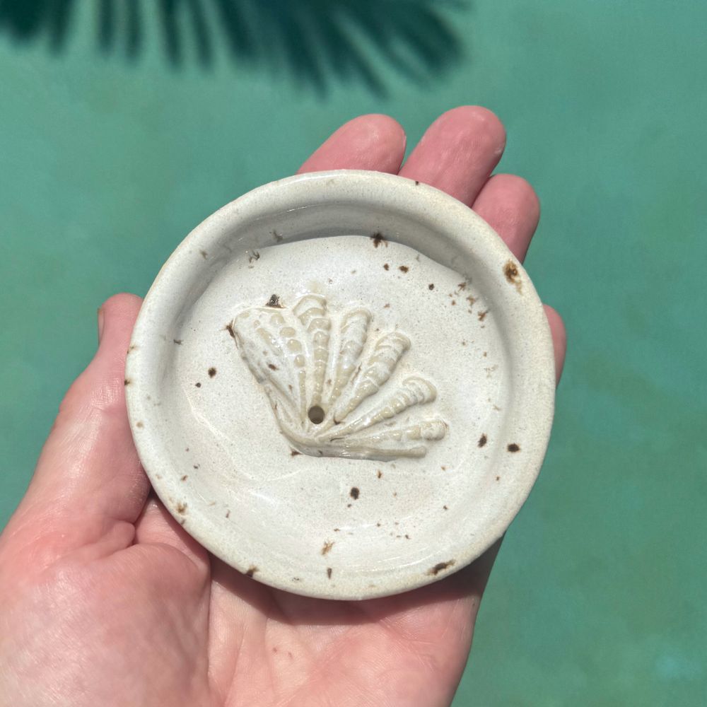 Hand holding a ceramic incense holder with shell design against a blurred natural background. Sunshine Pot-Tree