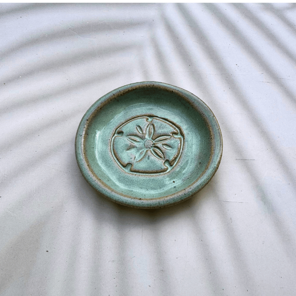 Green ceramic dish with a starfish design on a textured white surface