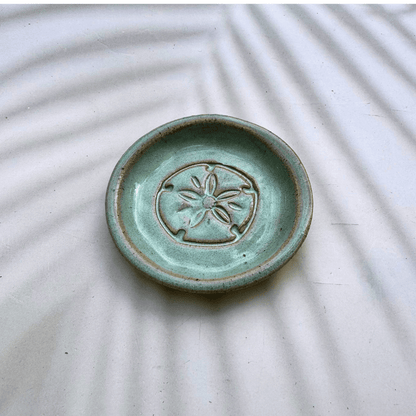 Green ceramic dish with a starfish design on a textured white surface