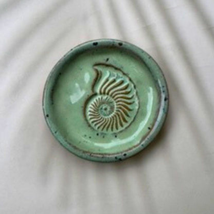 Green ceramic dish with a shell design on a beige background