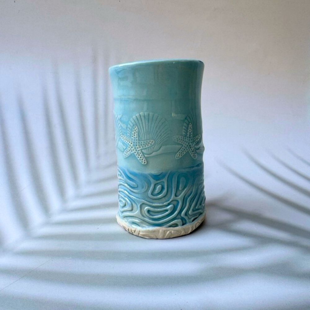 Ceramic bud vase with ocean-themed patterns on a white background