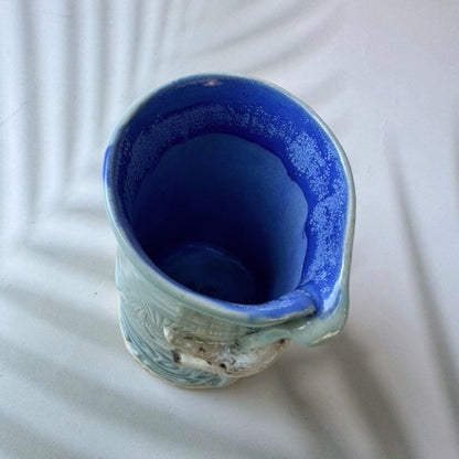 Blue ceramic bud vase with textured design on a white background
