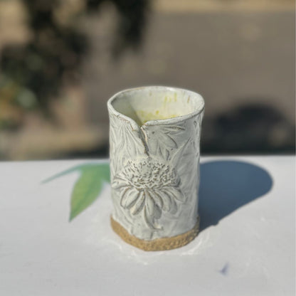 Ceramic vase with coneflower design on a blurred background