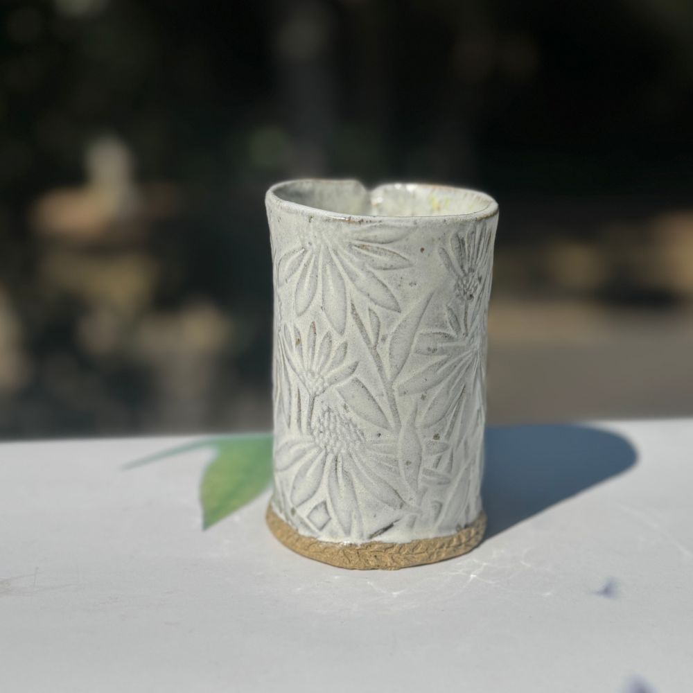 Ceramic vase with flower and leaf pattern on a blurred natural background