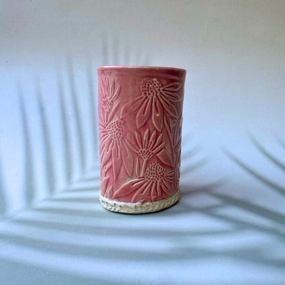 Pink ceramic vase with floral patterns on a white background