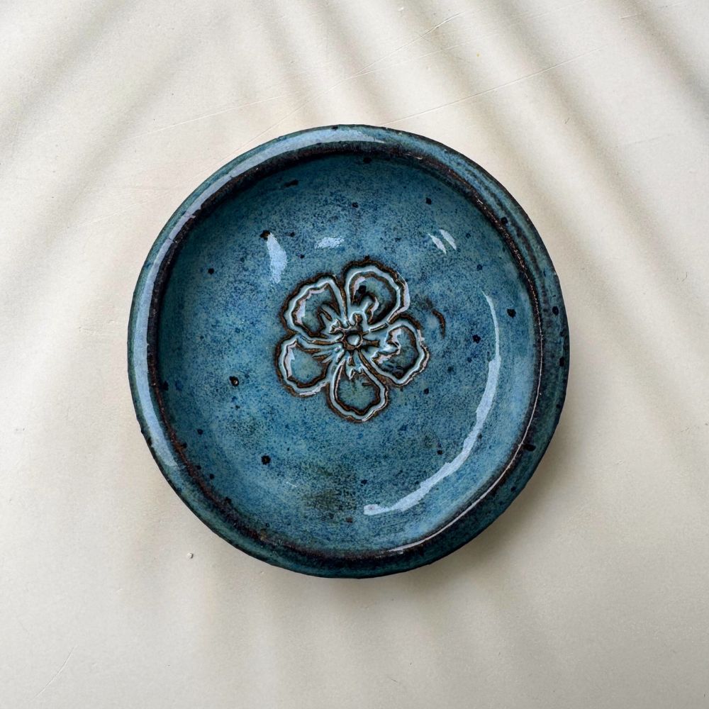 Blue ceramic ring dish with floral design on a beige background