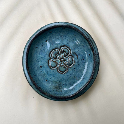 Blue ceramic ring dish with floral design on a beige background
