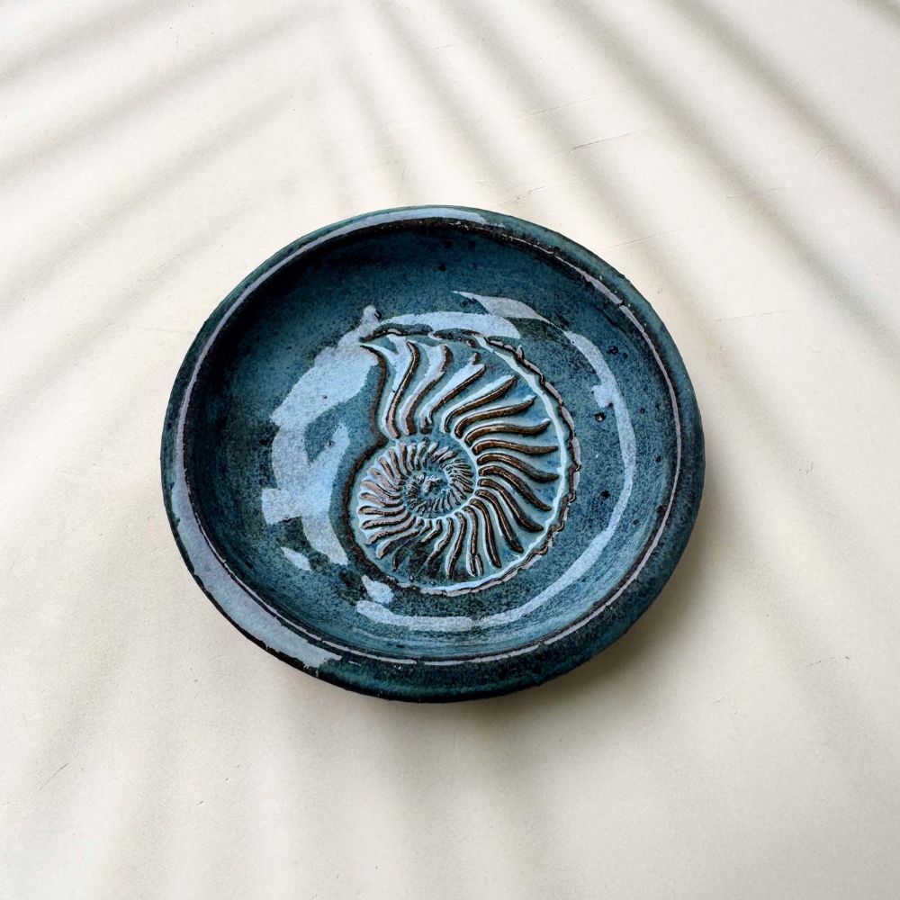 Blue ceramic ring dish with a shell pattern on a beige background