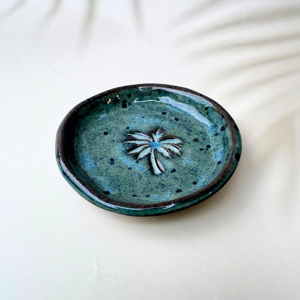 Green ceramic ring dish with a star design on a white background