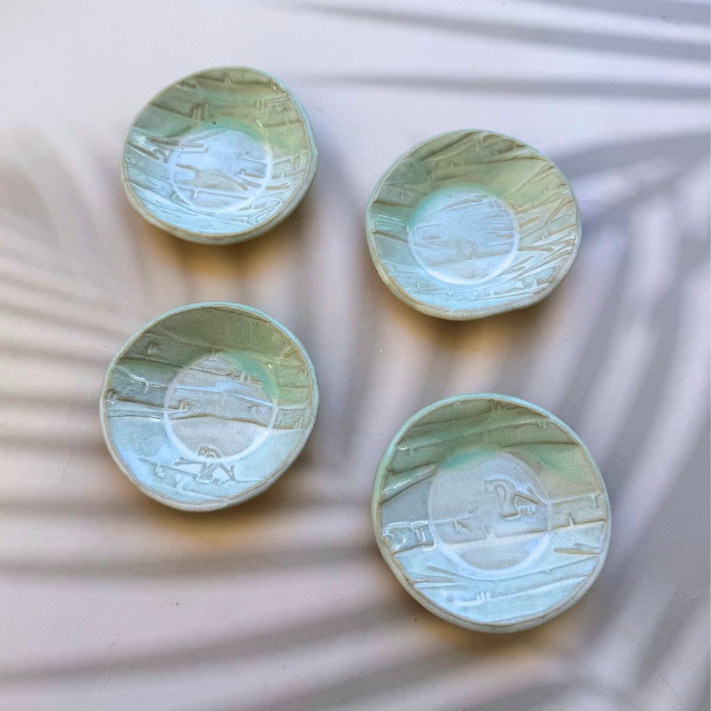 Four ceramic plates with textured surfaces on a textured white background. Sunshine Pot-Tree