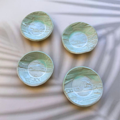 Four ceramic plates with textured surfaces on a textured white background. Sunshine Pot-Tree